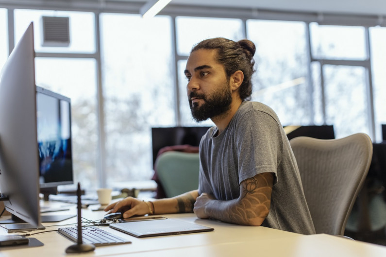 Young man in an office or library searches online for jobs